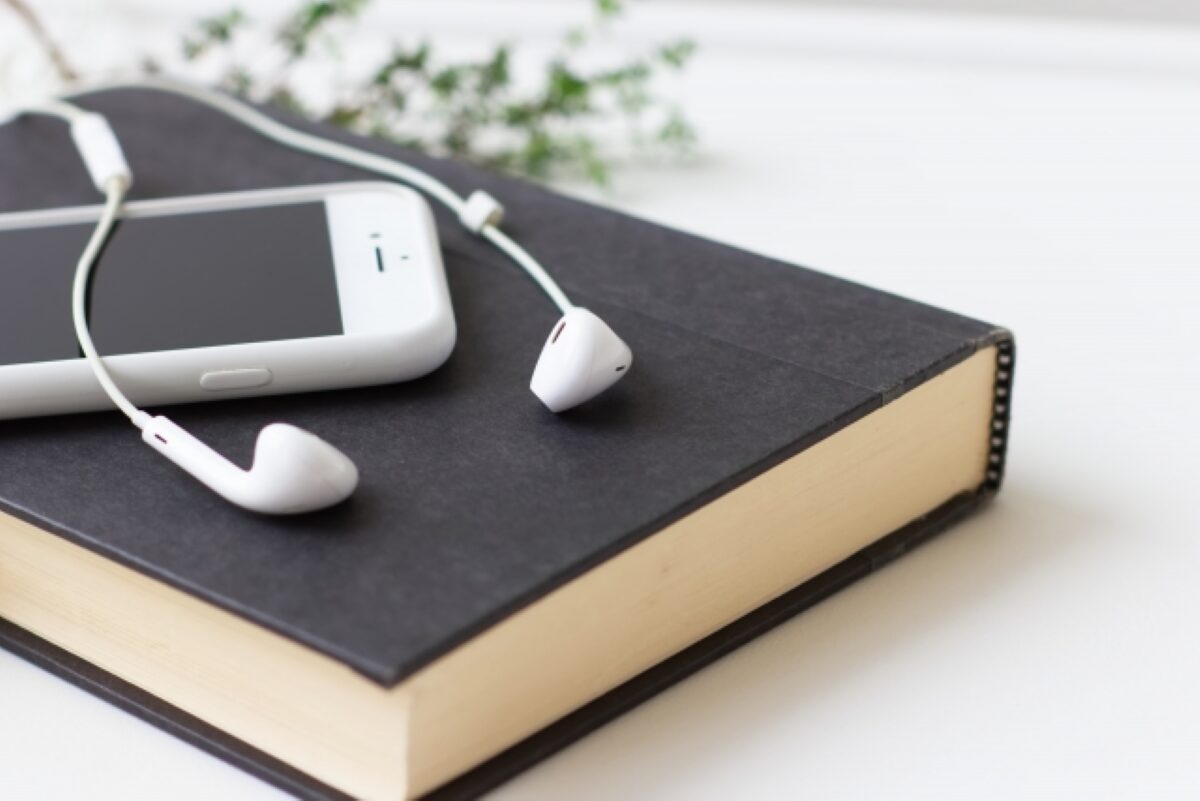 本とスマホとイヤホンの画像